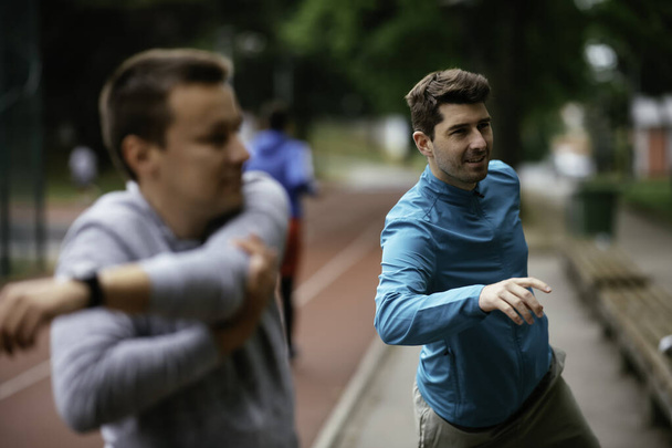 Young men exercising on a race track. Two young friends training outdoors. - Photo, Image