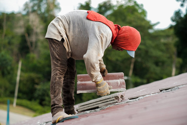 Працівники встановлюють черепицю. Будівництво даху будинку, керамічної плитки або бетонної черепиці
 - Фото, зображення