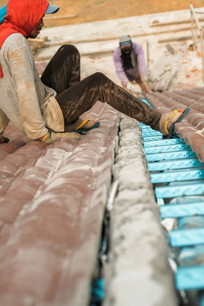 Рабочие устанавливают черепицу. Строительство крыши дома, керамической плитки или бетонной черепицы - Фото, изображение