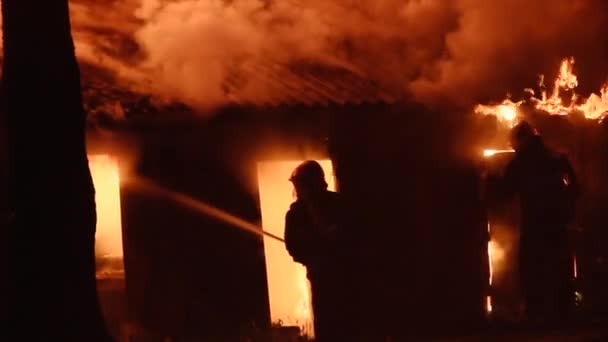 Nel fuoco di un edificio in legno, un vigile del fuoco irrompe nella porta. Lavori di soccorso. - Filmati, video