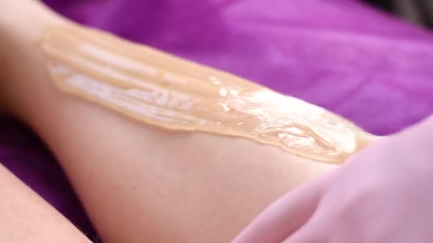 Kozmetikus gyantázza a nő lábát a szépségszalonban. A lábak nyírására vonatkozó eljárás. - Felvétel, videó