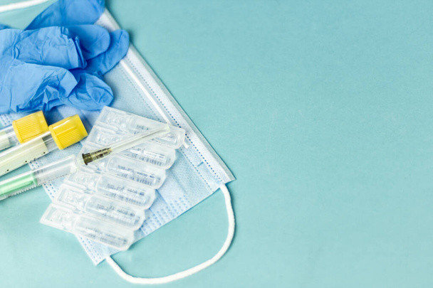 Medical vials for injection, syringe for injection, mask gloves on a blue background. Admission vaccination, flu shot - 写真・画像