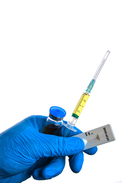 Male doctor hand in blue glove holds corona virus test, syringe and vial bottle with covid-19 vaccine dose. Coronavirus cure, flu medicine treatment vaccination concept. - Valokuva, kuva