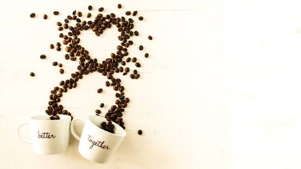 Tazze bianche con l'iscrizione Meglio insieme da cui escono i chicchi di caffè che formano un cuore. Sfondo bianco con spazio per mettere testo. Immagine perfetta per gli amanti del caffè - Foto, immagini