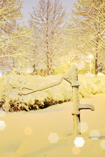 насос с водой, хорошо покрытый снегом, вечернее время, зима и снег - Фото, изображение