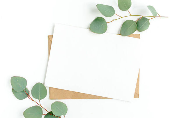 Invitation maquette, carte de vœux vierge et feuilles vertes d'eucalyptus. Couché plat, vue du dessus. - Photo, image