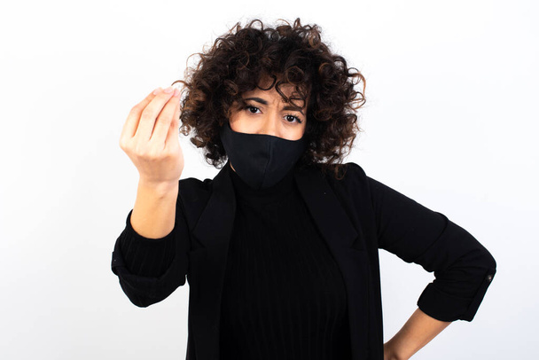 What the hell are you talking about. Shot of frustrated  caucasian woman wearing medical mask gesturing with raised hand doing Italian gesture, frowning, being displeased and confused with dumb question. - Fotoğraf, Görsel