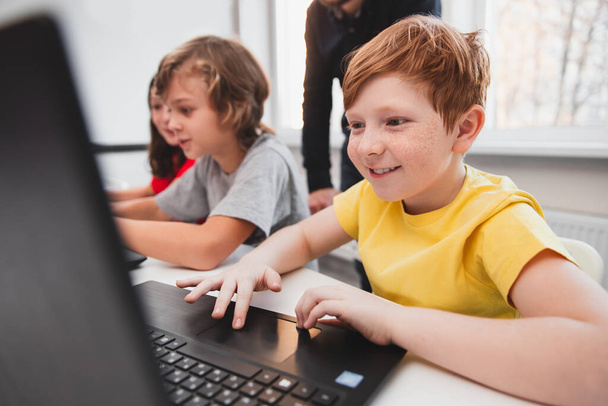 Excited boy working with laptop in classroom - Photo, Image