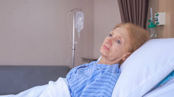 Lonely senior woman lying on bed at hospital - Zdjęcie, obraz