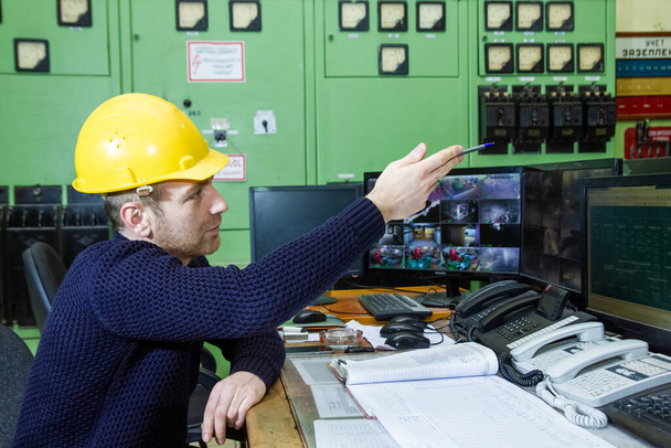 Elektrik santralinde çalışan sarı kasklı elektrikçi. - Fotoğraf, Görsel