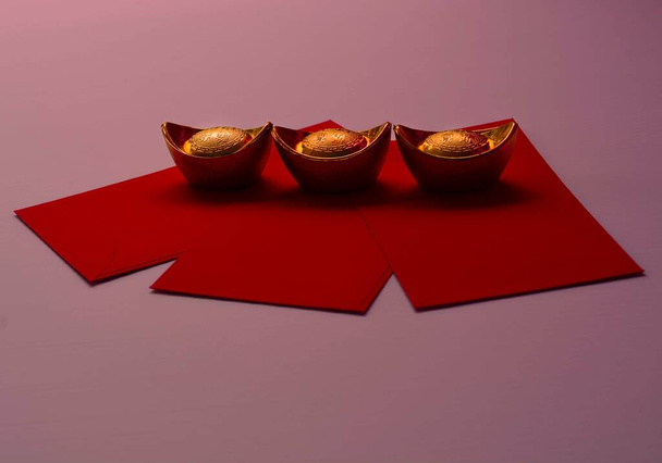 Chinese New Year Spring festival decorations pow or red packet and gold ingots or golden lump on a pink background - Photo, Image