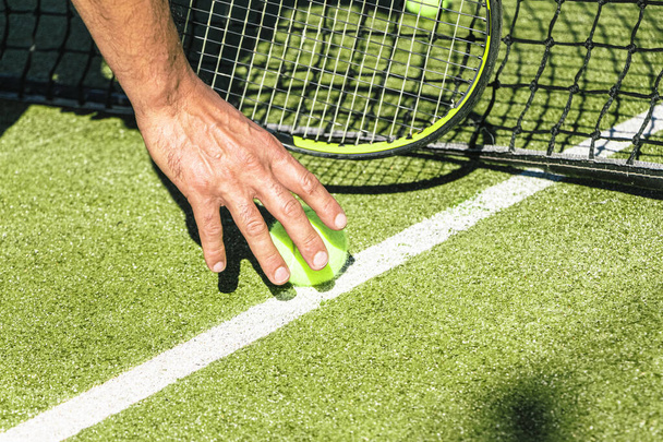 Hombre recogiendo una pelota de tenis del campo de tenis - Foto, Imagen