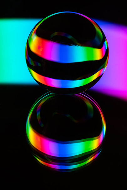 Glaskristallkugel auf Spiegeloberfläche mit einem rgb mehrfarbigen Muster Lichtmalerei Fraktale auf schwarzem Hintergrund - Foto, Bild