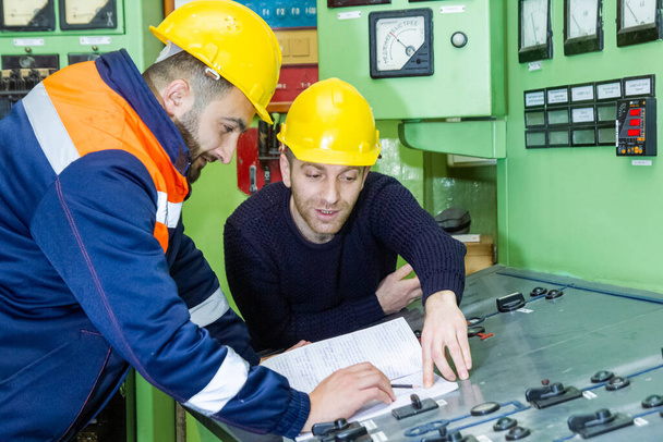 elettricisti con casco giallo che lavorano in una centrale elettrica - Foto, immagini
