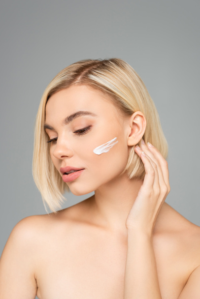 Woman with clean skin applying cosmetic cream isolated on grey  - Zdjęcie, obraz