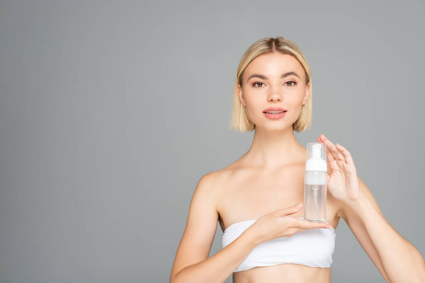 Blonde woman in white top posing with cleansing foam isolated on grey  - Foto, afbeelding
