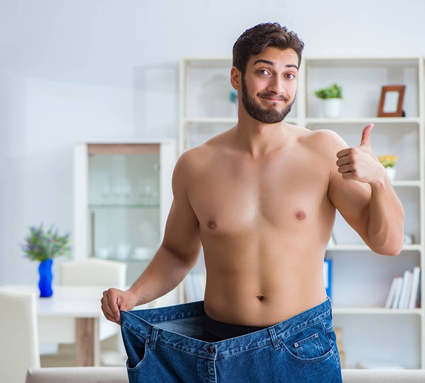 Man in oversized pants in weight loss concept - Фото, изображение
