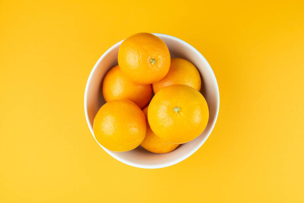directement au-dessus de la vue du bol blanc rempli d'oranges juteuses - Photo, image