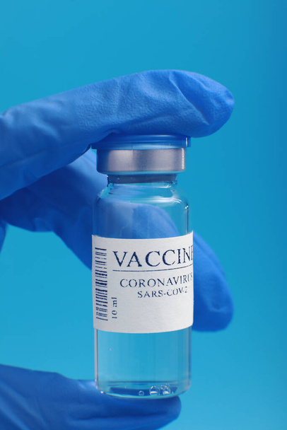 Desarrollo y creación de una vacuna contra el coronavirus COVID-19 .Vacuna contra el Coronavirus en frasco de vidrio en la mano del médico sobre fondo azul. Vacuna Concepto de lucha contra el coronavirus - Foto, Imagen
