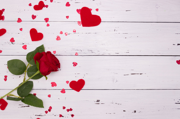 Rosa y corazones rojos sobre un fondo de madera blanca, vista superior. Copyspace, un concepto del Día de San Valentín. - Foto, imagen
