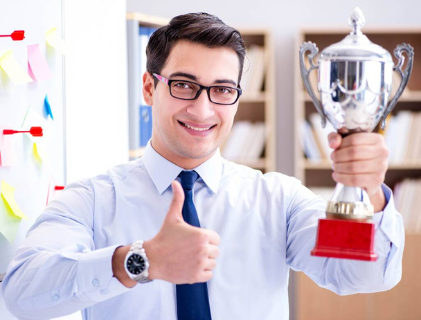 Joven hombre de negocios recibiendo premio taza en la oficina - Foto, Imagen