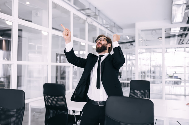 Giovane pazzo bell'uomo d'affari che balla nella lobby aziendale in giacca e cravatta per celebrare i risultati raggiunti - Foto, immagini
