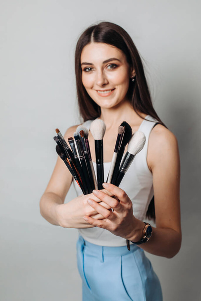 make-up artist's brushes in the hands in the foreground. on a light background, isolated - Zdjęcie, obraz