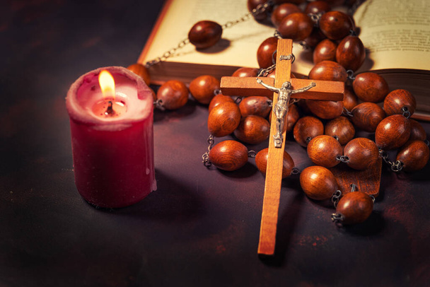 Big wooden Rosary beads and crucifix cross with jesus,red candle and bible book,spiritual atmosphere ,religion concept. - Foto, Imagen