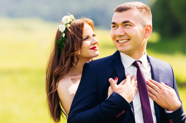 Happy bride and groom are walking and hugging on a summer meadow. Romantic married young family. - Φωτογραφία, εικόνα