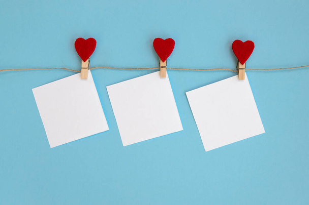 Zarf ve kırmızı kalpler, mavi arka planda asılı duruyor. Sevgililer Günü dekorasyonu. - Fotoğraf, Görsel