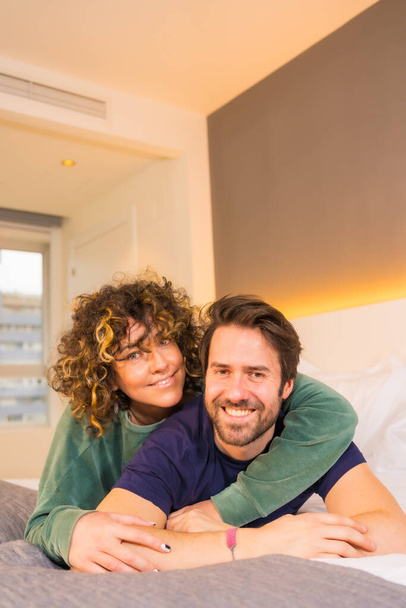 Lifestyle, portrait of a young Caucasian couple in pajamas on the bed - Foto, imagen