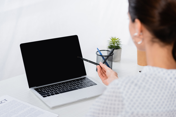 blurred businesswoman looking at laptop with blank screen - Photo, Image