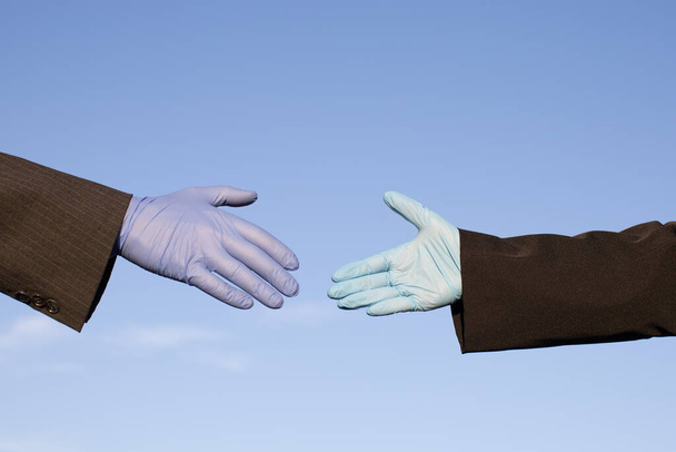 business partners wearing protective gloves and reaching out for handshake - Foto, Bild