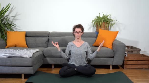Lady dziewczyna 30 lat robi jogi siłownia medytacji podczas Covid-19 Coronavirus zamknięcie domu kwarantanny - styl życia w salonie - Materiał filmowy, wideo