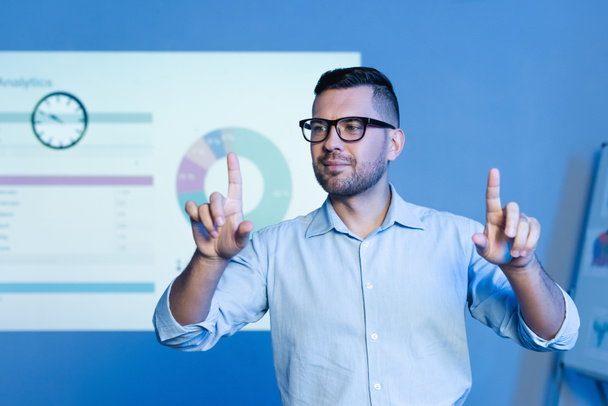 businessman in glasses pointing with fingers near charts and graphs on wall - Photo, Image