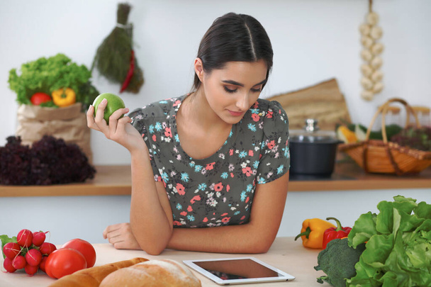 Young hispanic woman or student cooking in kitchen. Girl using tablet to make online shopping or find a new recipe. - Foto, Bild