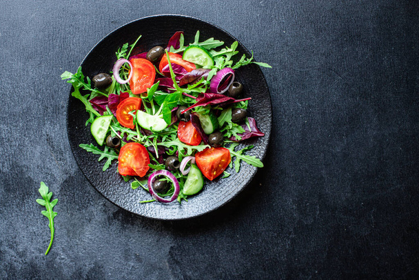 zöldség saláta paradicsom, arugula, saláta, olajbogyó zöldség gyorsétterem kész enni része az asztalon az egészséges étel snack kültéri felülnézet másolási hely szöveges élelmiszer háttér rusztikus kép keto - Fotó, kép
