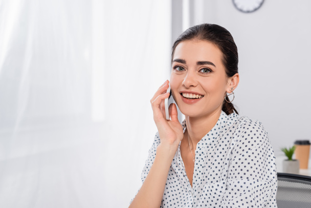 happy businesswoman talking smartphone and looking at camera - Фото, изображение