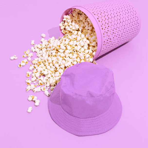 Mínimo monocromo palomitas de maíz púrpura cubo y sombrero. Diseño de naturaleza muerta. Concepto de cine casero de moda - Foto, Imagen