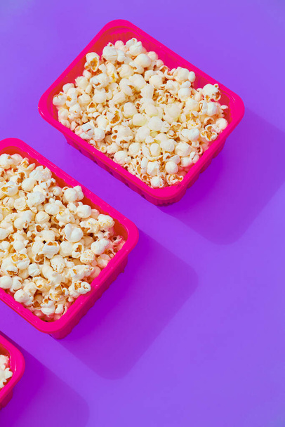 Minimal popcorn set plastic box on purple background. Isometry trendy vertical design. Fast food, Home cinema concept - Photo, Image