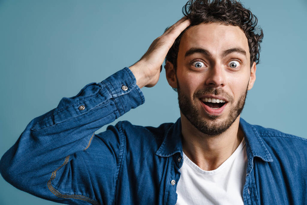 Shocked caucasian guy expressing surprise on camera isolated over blue background - Foto, immagini