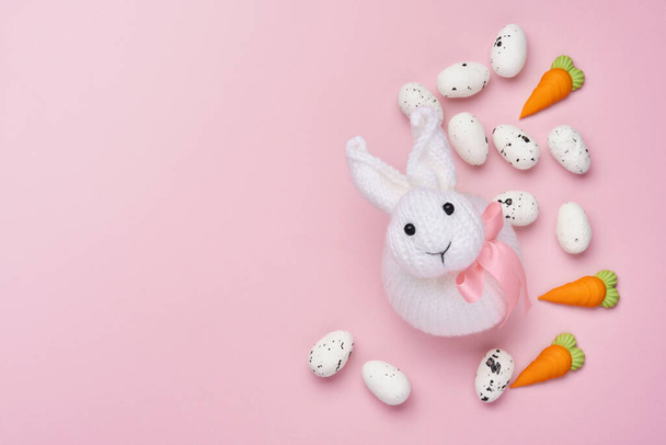 Tarjeta de felicitación de primavera de Pascua con conejo, huevos y zanahoria dulce sobre fondo rosa. Vista superior. - Foto, imagen