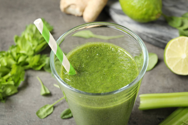 Green juice and fresh ingredients on grey table, closeup - 写真・画像