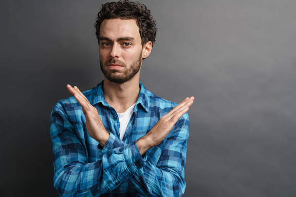 Unshaven tense guy showing stop gesture on camera isolated over grey background - Fotoğraf, Görsel
