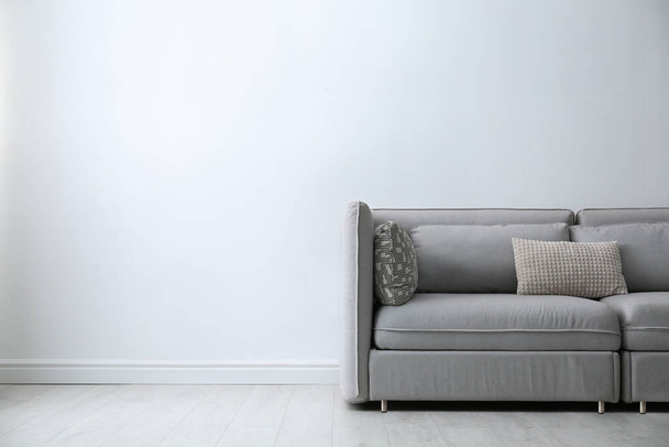 Grey sofa with pillows near white wall in stylish living room interior. Space for text - Foto, immagini