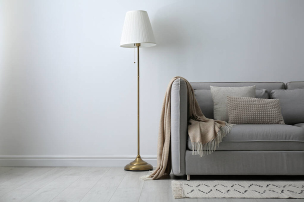 Grey sofa with pillows near white wall in stylish living room interior - Foto, Bild