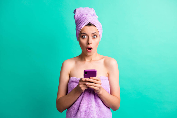 Photo of amazed scared young lady hold telephone hands check time late wear violet towels isolated teal color background - Foto, immagini