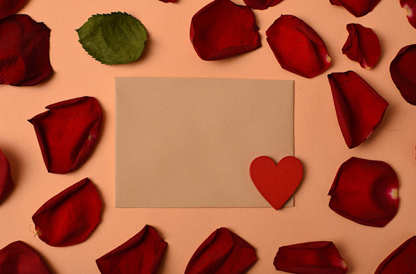 Rózsaszirmokkal és szívvel körülvett boríték. A szerelem és a romantika szimbóluma - Fotó, kép