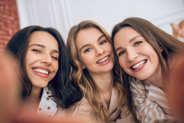 Three girls making selfie and looking happy - Fotó, kép