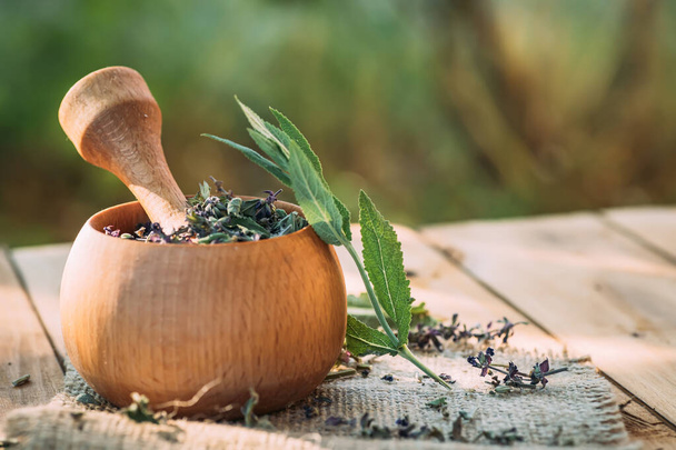 Wooden mortar with cooked dried herb Salvia pratensis. Medicinal herbs. self-medication. - Photo, Image